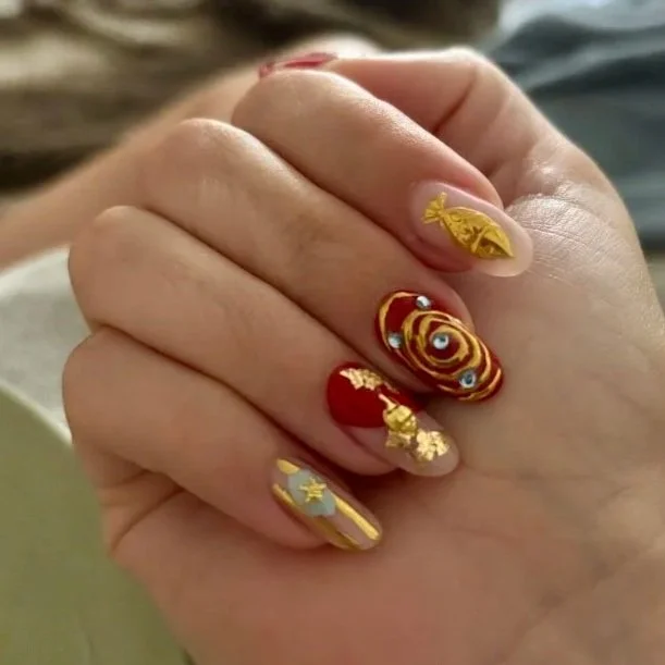 Close-up of a hand showcasing decorated nails with Christmas-themed nail art, including gold designs, a candy cane, and swirl patterns.
