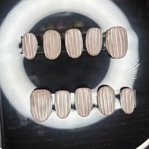 Two strings of brown, oval-shaped beads with vertical lines, placed on a reflective surface with a white ring and black background.