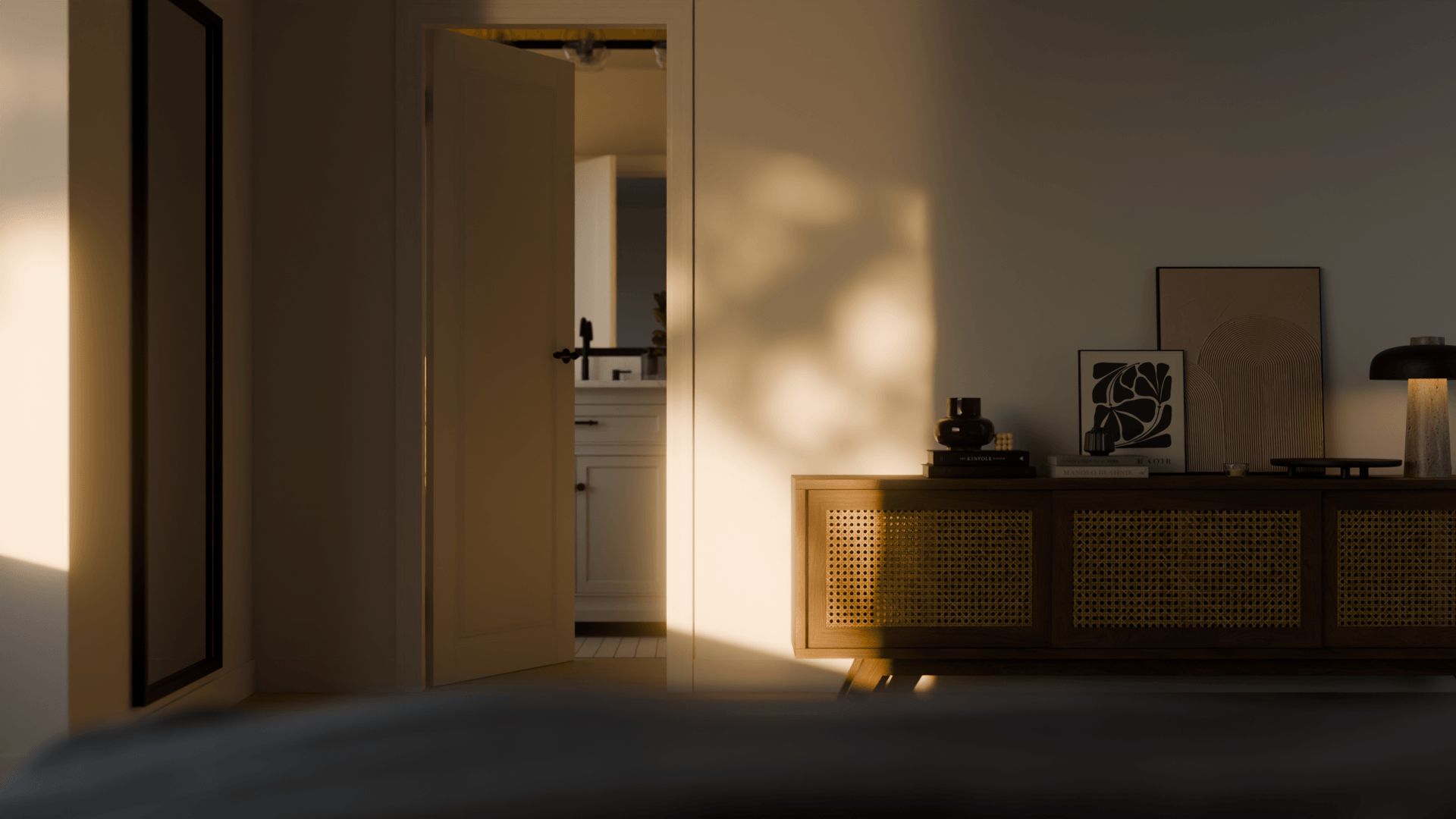 Interior view of a room with a wooden sideboard decorated with framed abstract art, books, and a black lamp, illuminated by natural light.