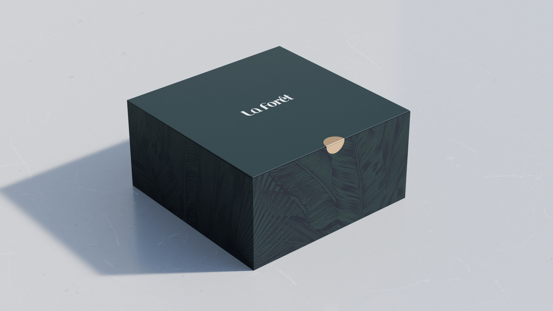 A black box with green leaf patterns and the words "La Forêt" on the top, positioned on a light gray surface.