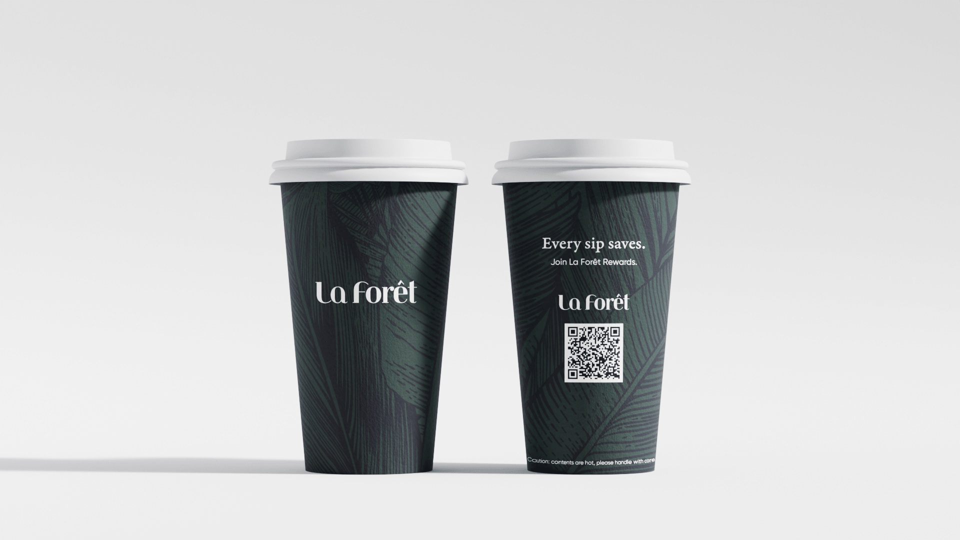 Two dark green paper coffee cups with white lids, featuring a leaf pattern and the words "La Forêt" on the front, placed against a plain white background.