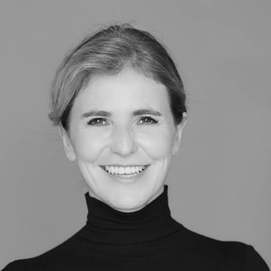 Black and white portrait of a woman with short hair, smiling, wearing a black turtleneck.