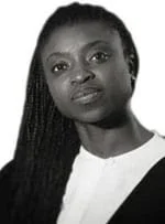 Black and white portrait of a woman with long braided hair, wearing a white top with a black collar, looking at the camera with a serious expression.