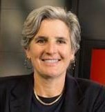 A woman with short gray hair smiling, wearing a dark blazer.