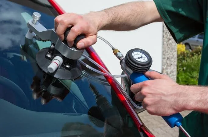 A person using a diagnostic tool on a car windshield to check for air leaks