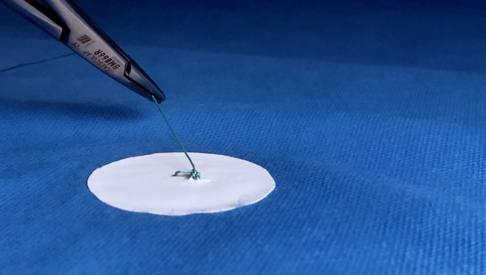 OneKnot green suture knot being cut.