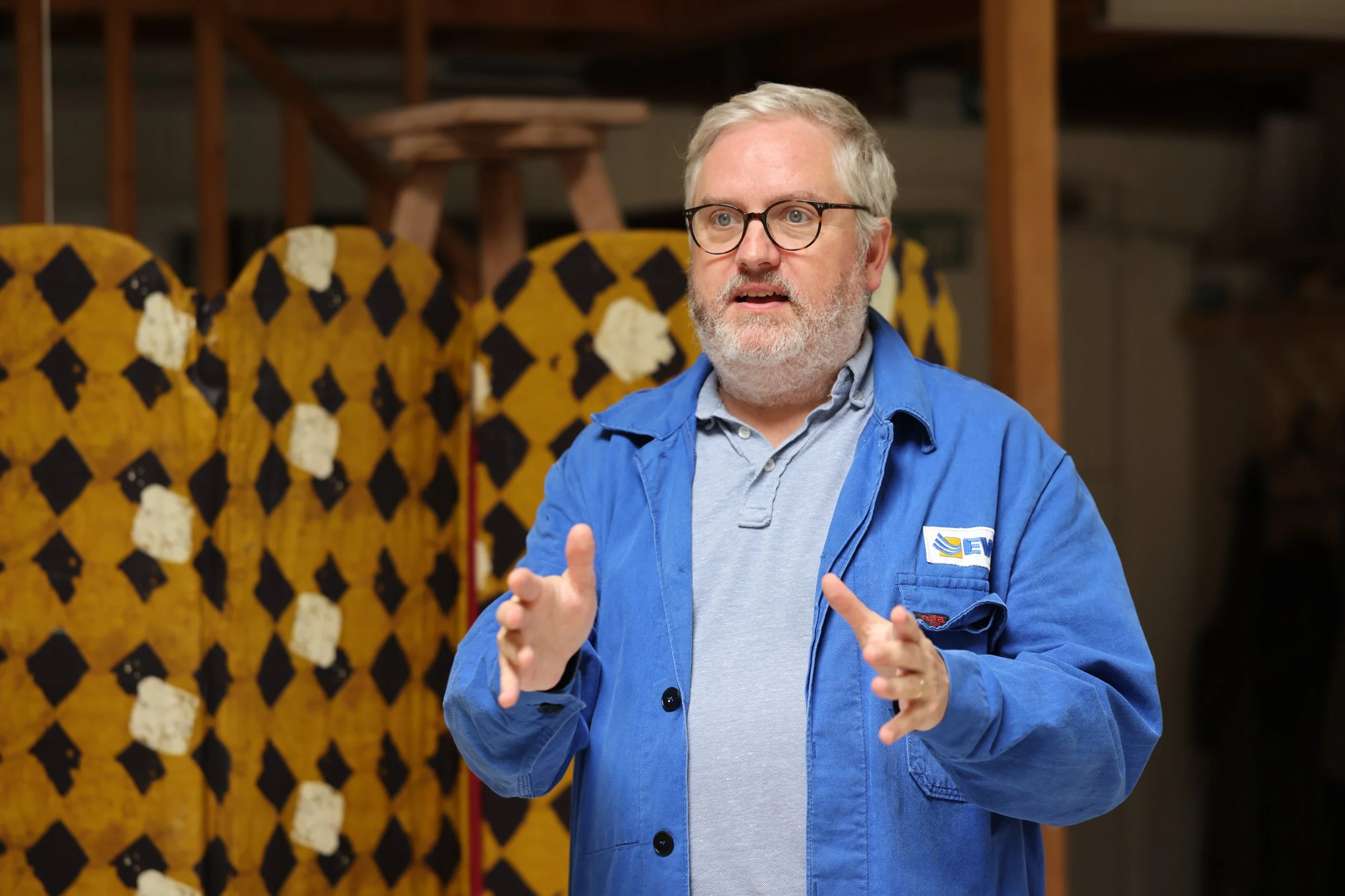 Benjamin Verrall speaking at an event in front of a colourful stage backdrop.