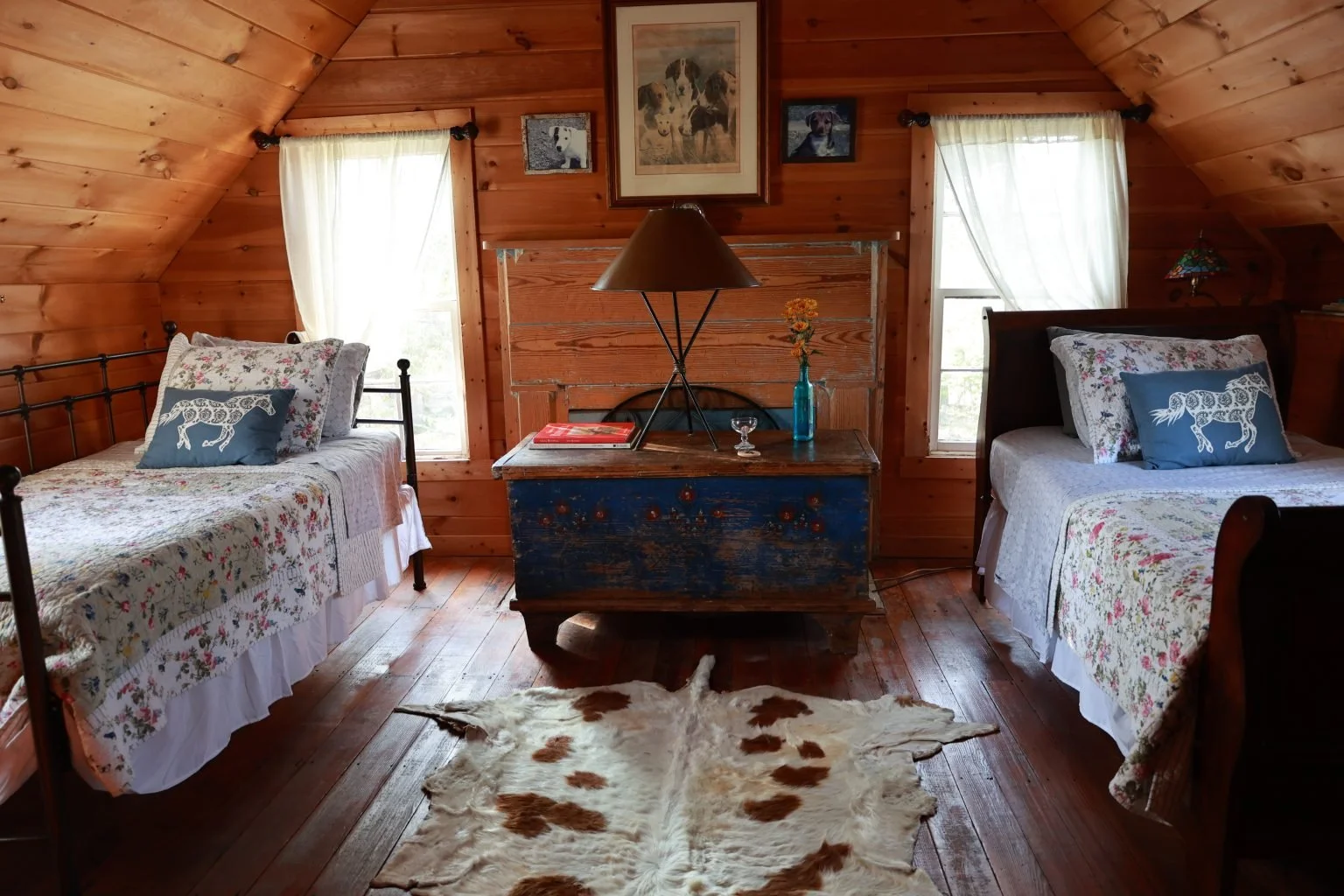 Hobart’s Room with twin beds, a blue antique trunk, and wood-paneled walls