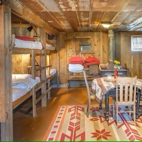 Saddle House with built-in wood bunk beds, ranch saddles, and a round dining table