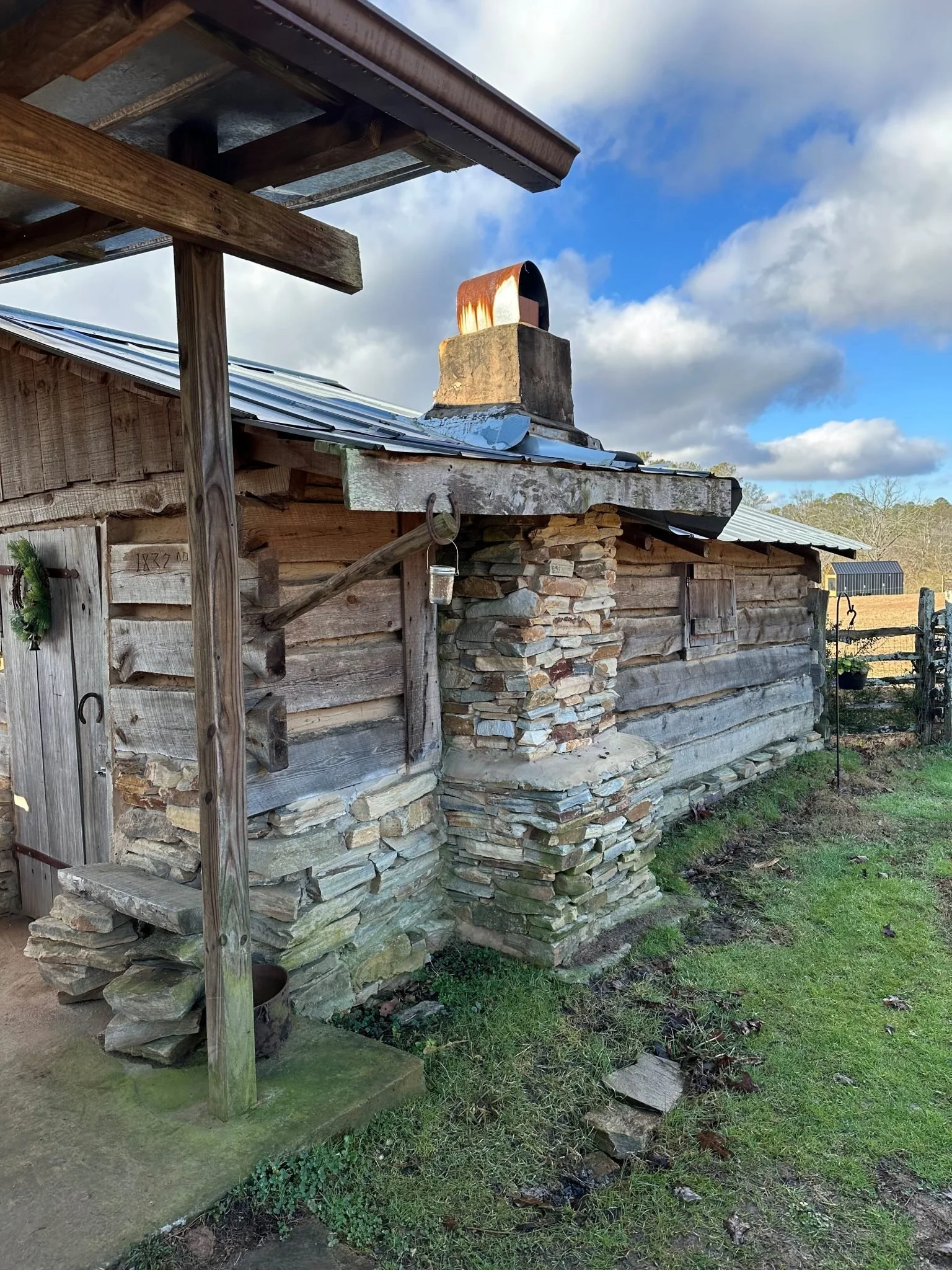 Rustic timber Cowboy Cabin with its stone chimney beside the ranch pasture