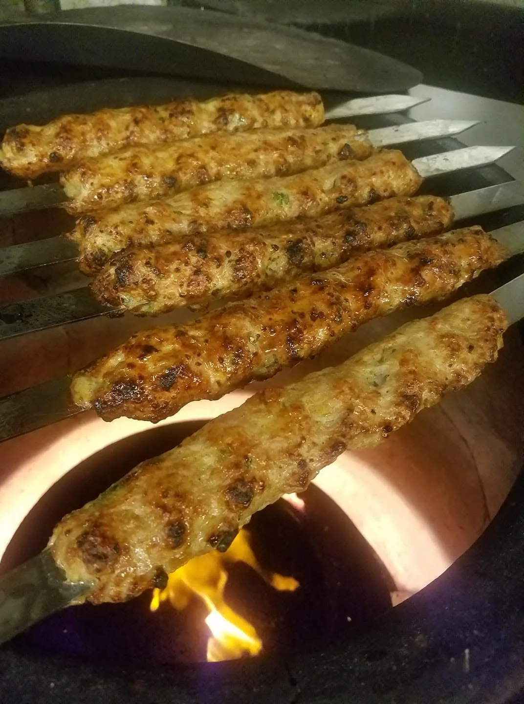 Skewers of grilled chicken being cooked over an open flame.