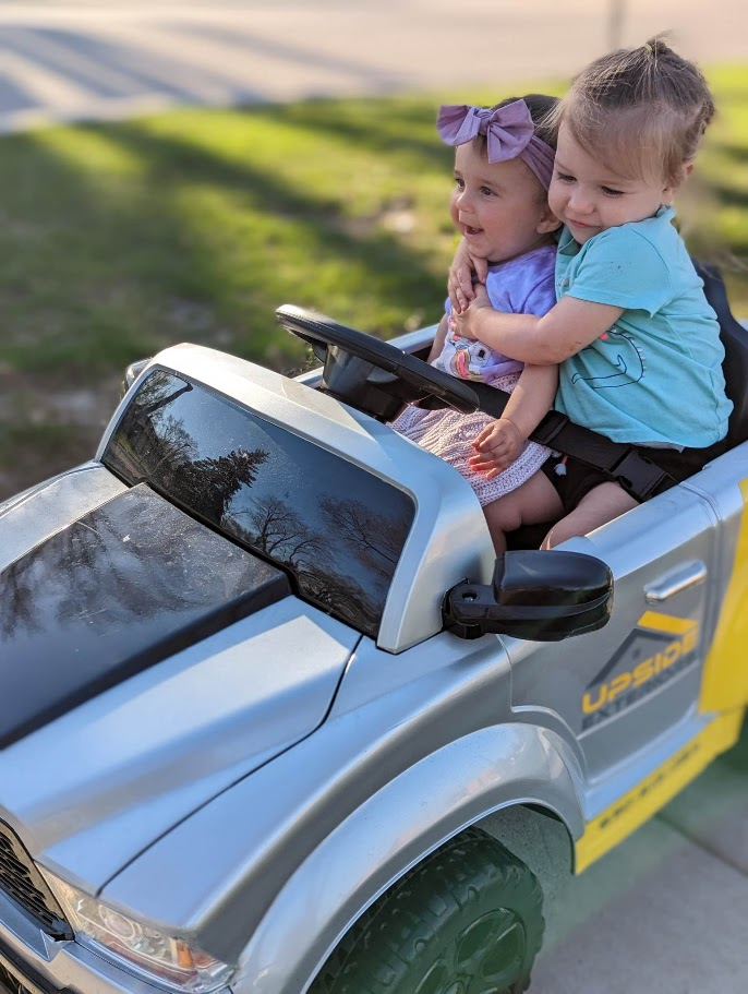 Two young daughters together in the miniature Upside Exteriors truck.