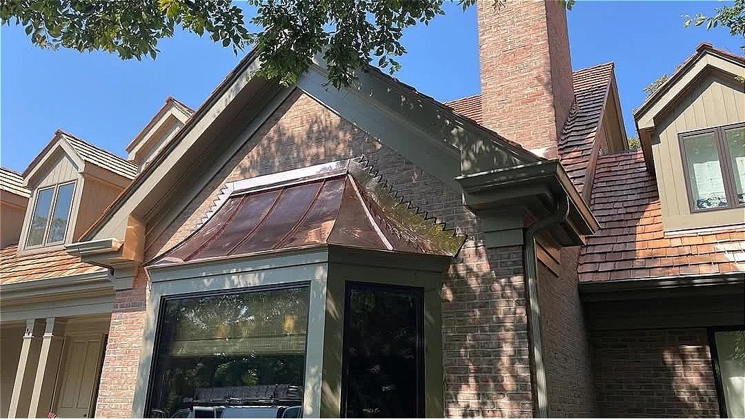 Custom copper roofing beside a cedar shake roof