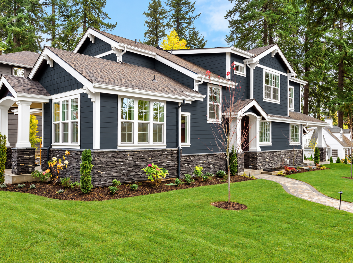 Dark gray siding with white trim and stone accents on a completed home