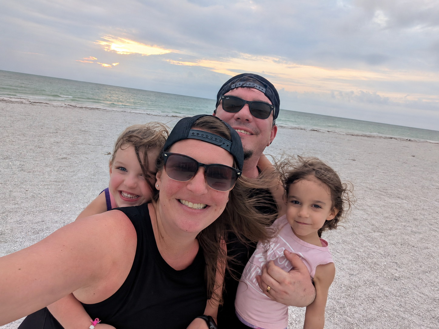 Jef and Stacey Eblen with their daughters on the beach; Jef wearing black Ray-Ban sunglasses