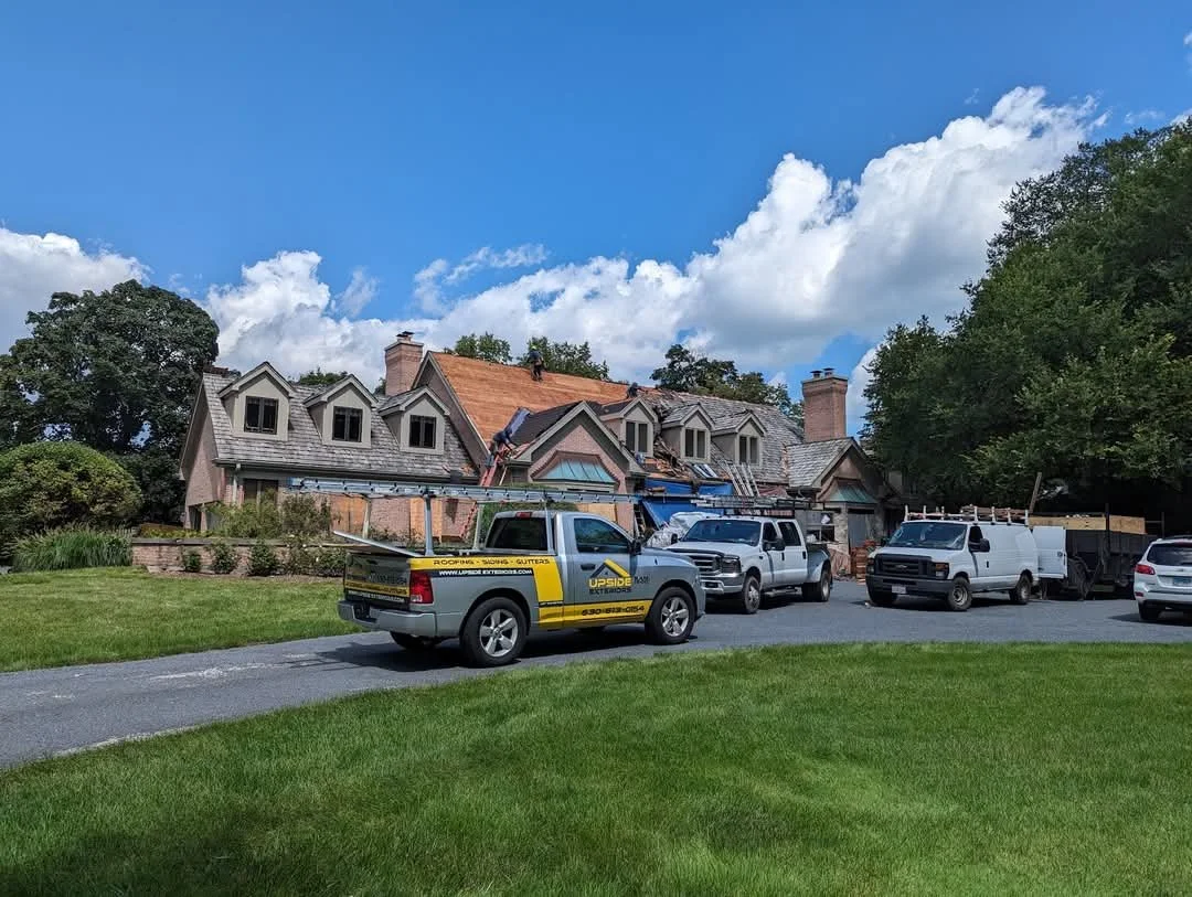 Exterior roofing project with crew trucks at the property