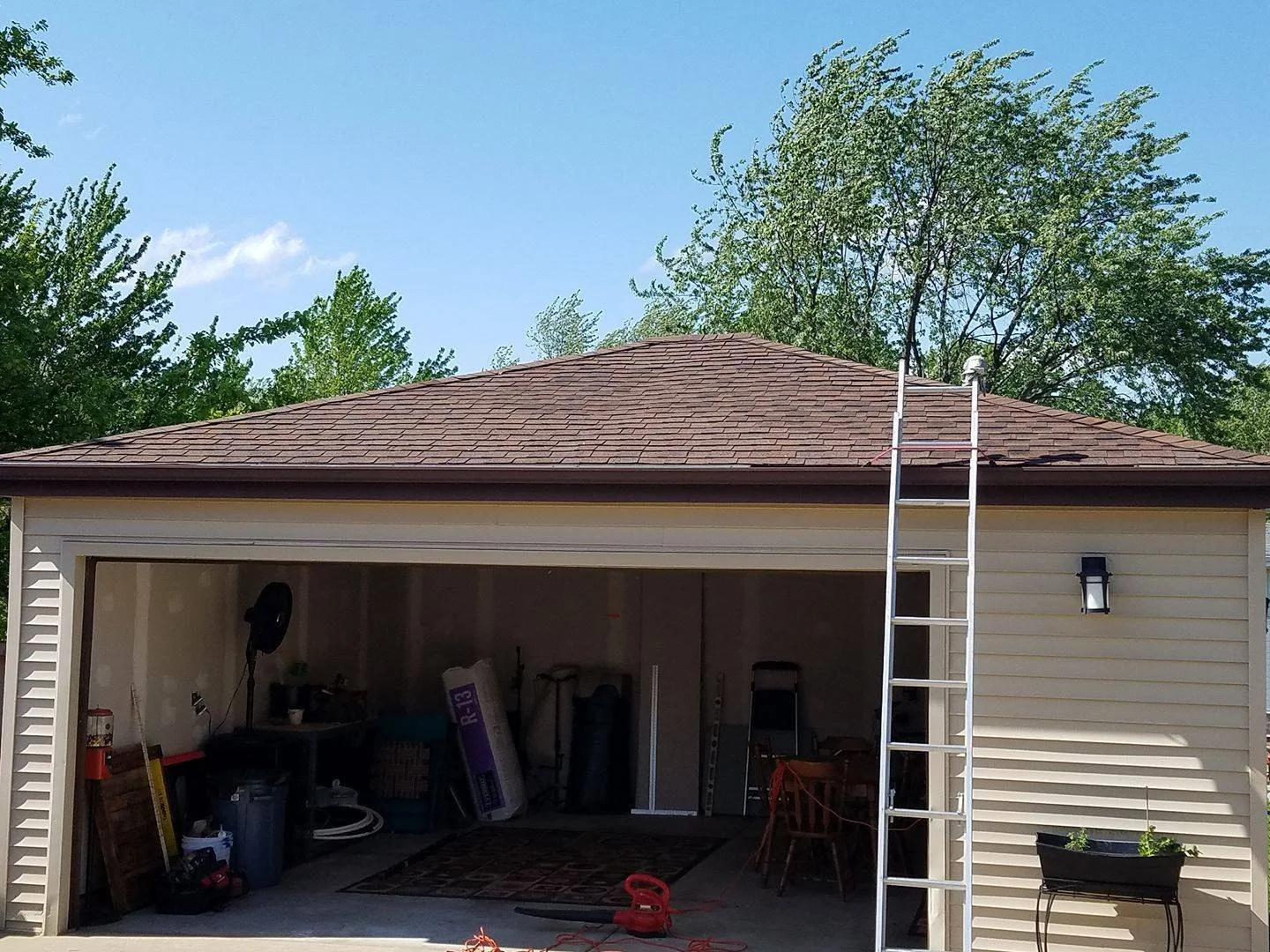 Garage roof after shingle repair with ladder at the roofline