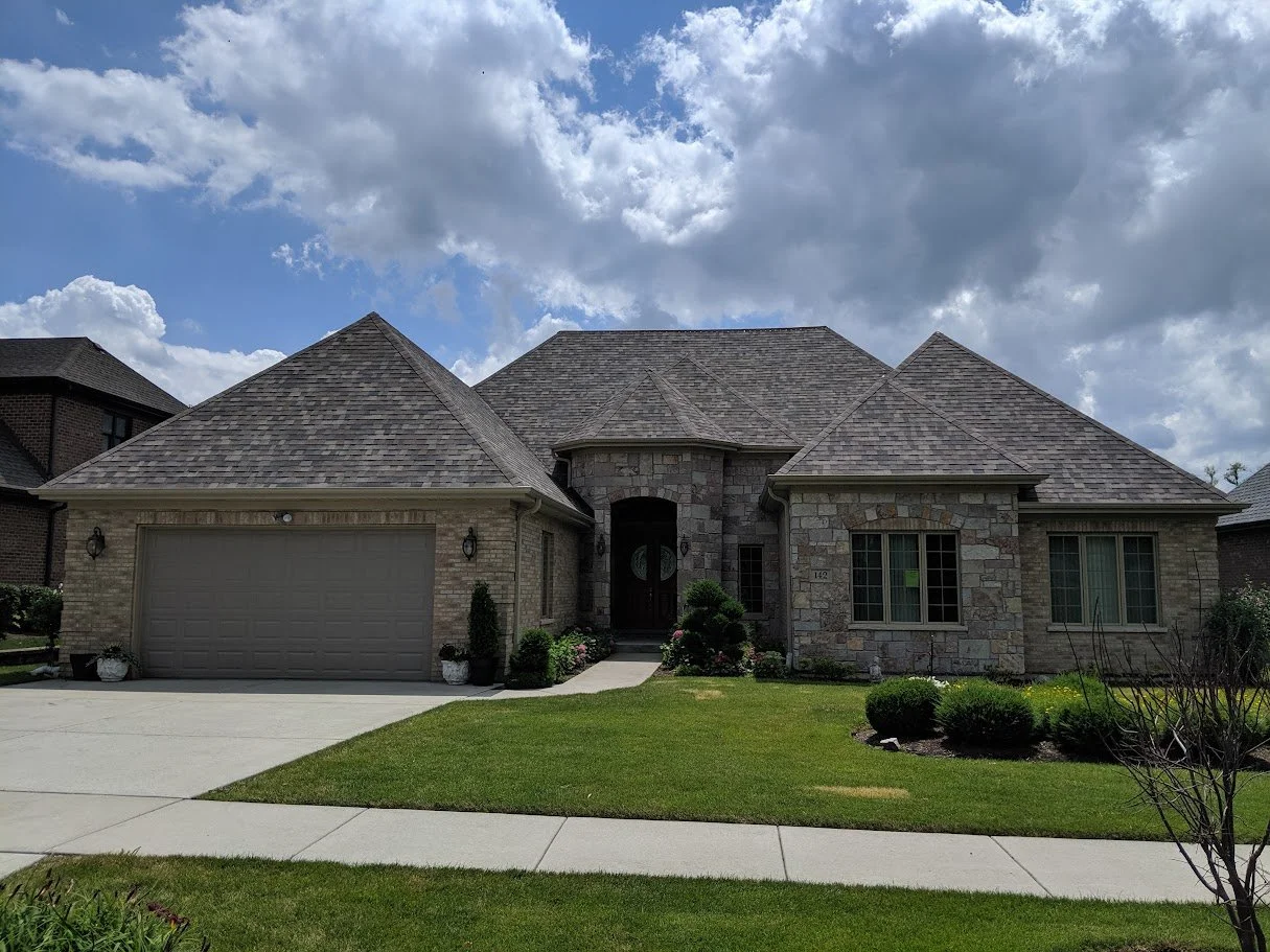 Completed gray shingle roof on a stone home