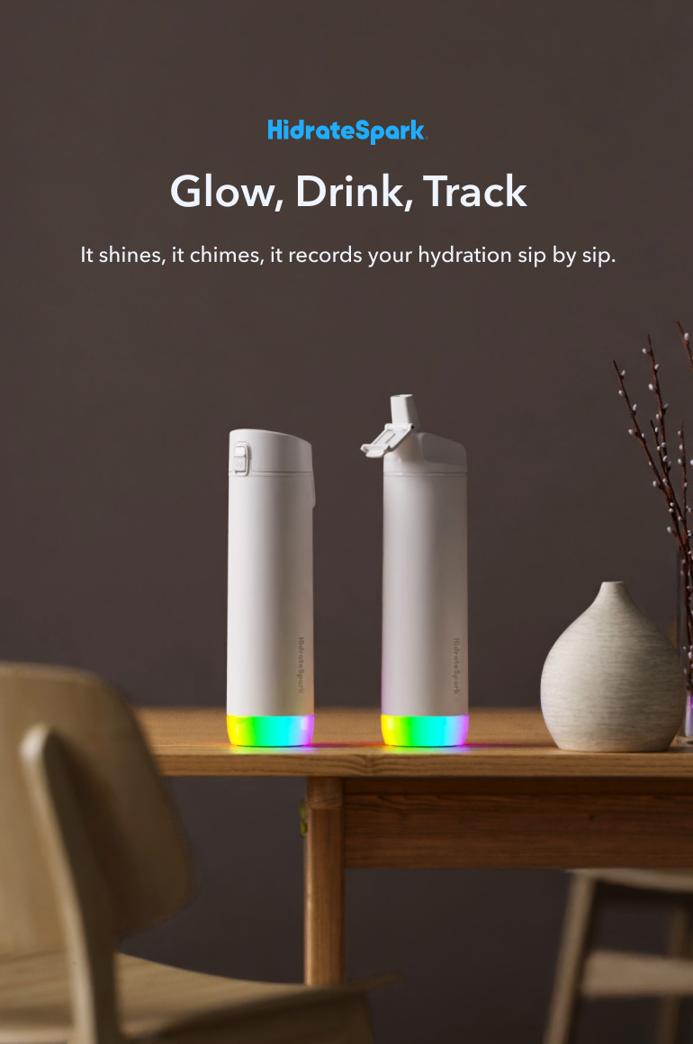 Two white HidrateSpark smart water bottles with glowing multicolor bases on a wooden table