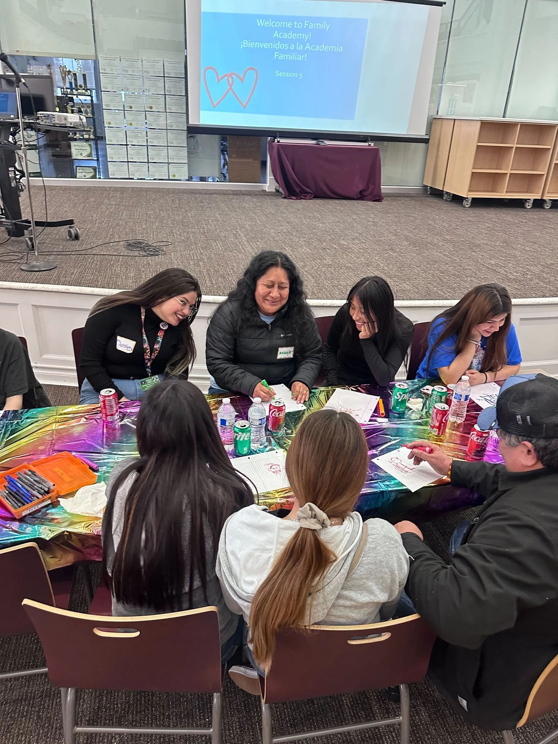 Families and Open School staff gathered around a table at a Step Up family event