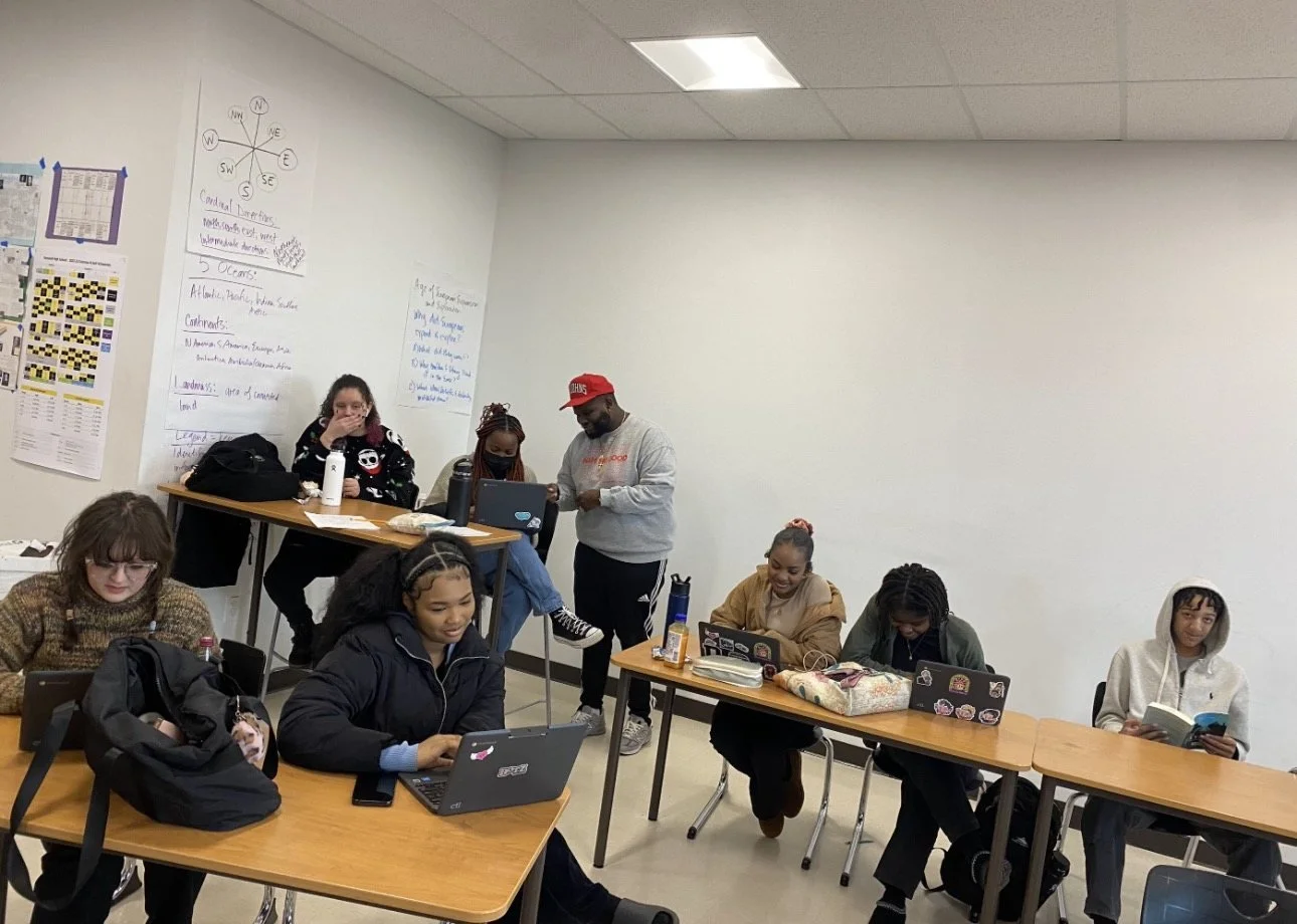 Students studying at desks with tutors in a Step Up after-school tutoring classroom