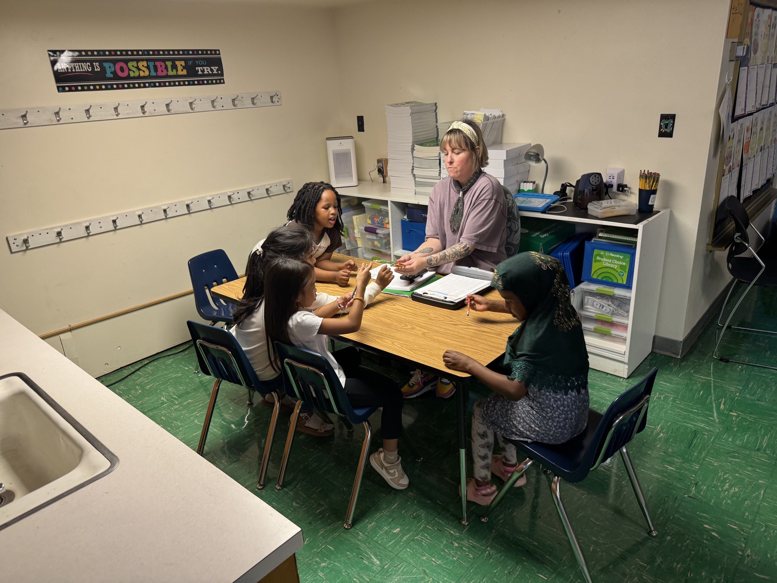 Adults and children seated together around a table in a Literacy Liberators small-group tutoring session