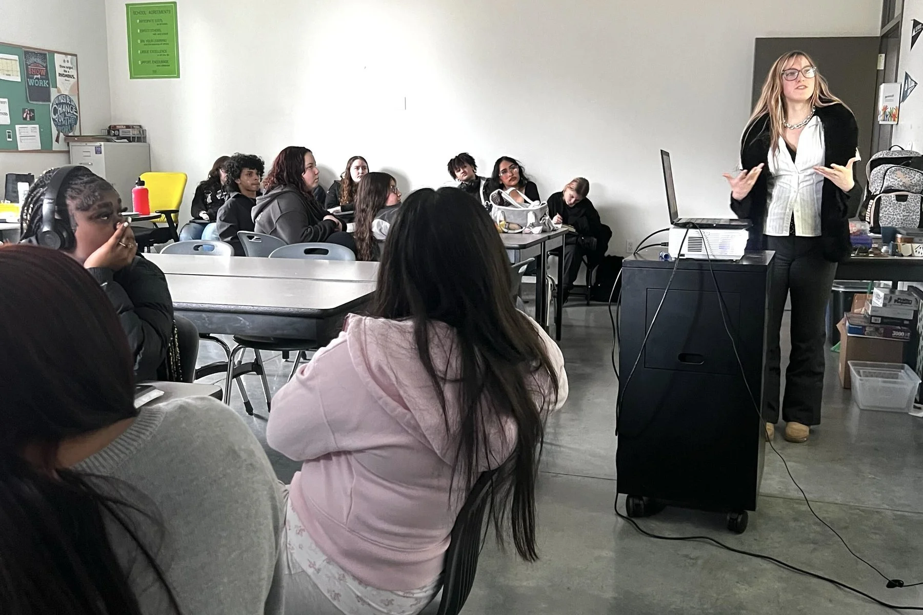 A staff member presenting to a classroom of Open School East students seated at tables