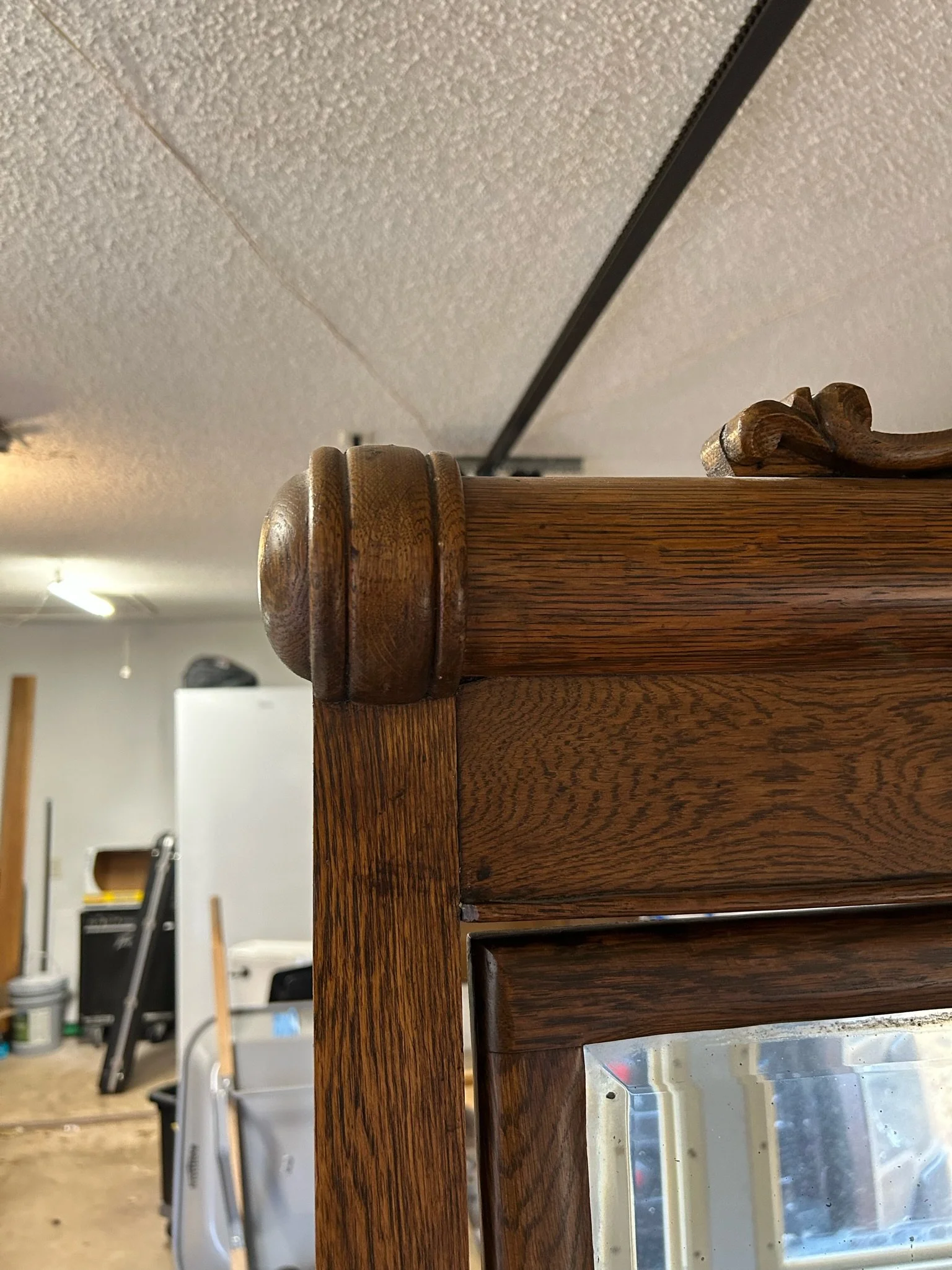 Close-up of a wooden piece of furniture, showcasing the detailed grain and craftsmanship, with a workshop setting in the background.