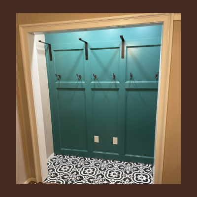Empty closet with teal walls, black hooks, and a patterned black and white tile floor.