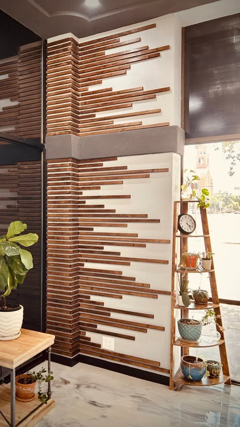 Interior corner of a modern room with a textured accent wall made of horizontal wooden slats, a wooden ladder shelf with potted plants, a large window, and a marble floor.