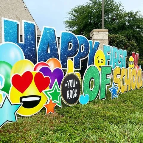 Colorful sign celebrating the first day of school with cheerful emojis, balloons, and star decorations.