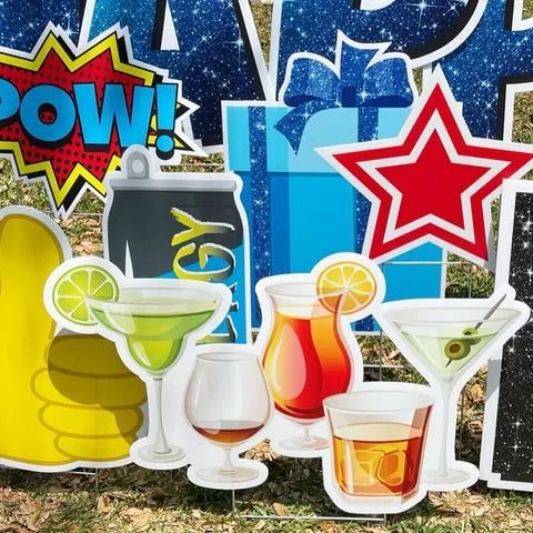 Colorful birthday party decorations with comic book style words like "POW!" and images of drinks including margarita, whiskey, and cocktail, along with a blue gift box, star shape, and atom style background.