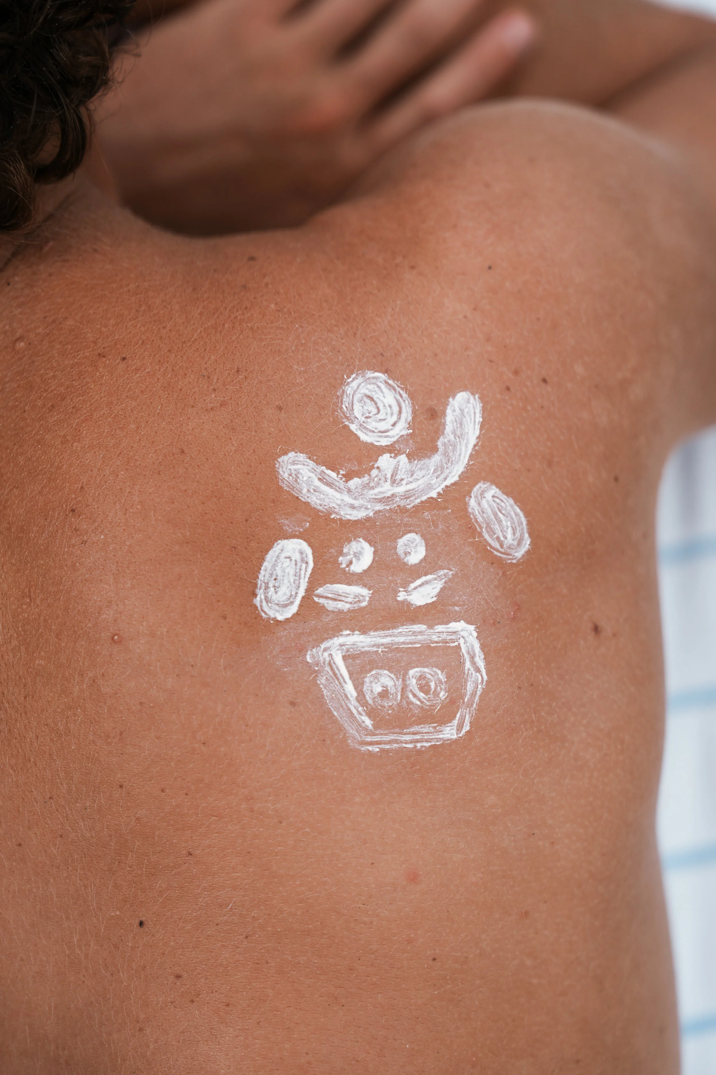 Back of a person with watermarked white paint forming a smiley face and a stack of blocks on their shoulder.