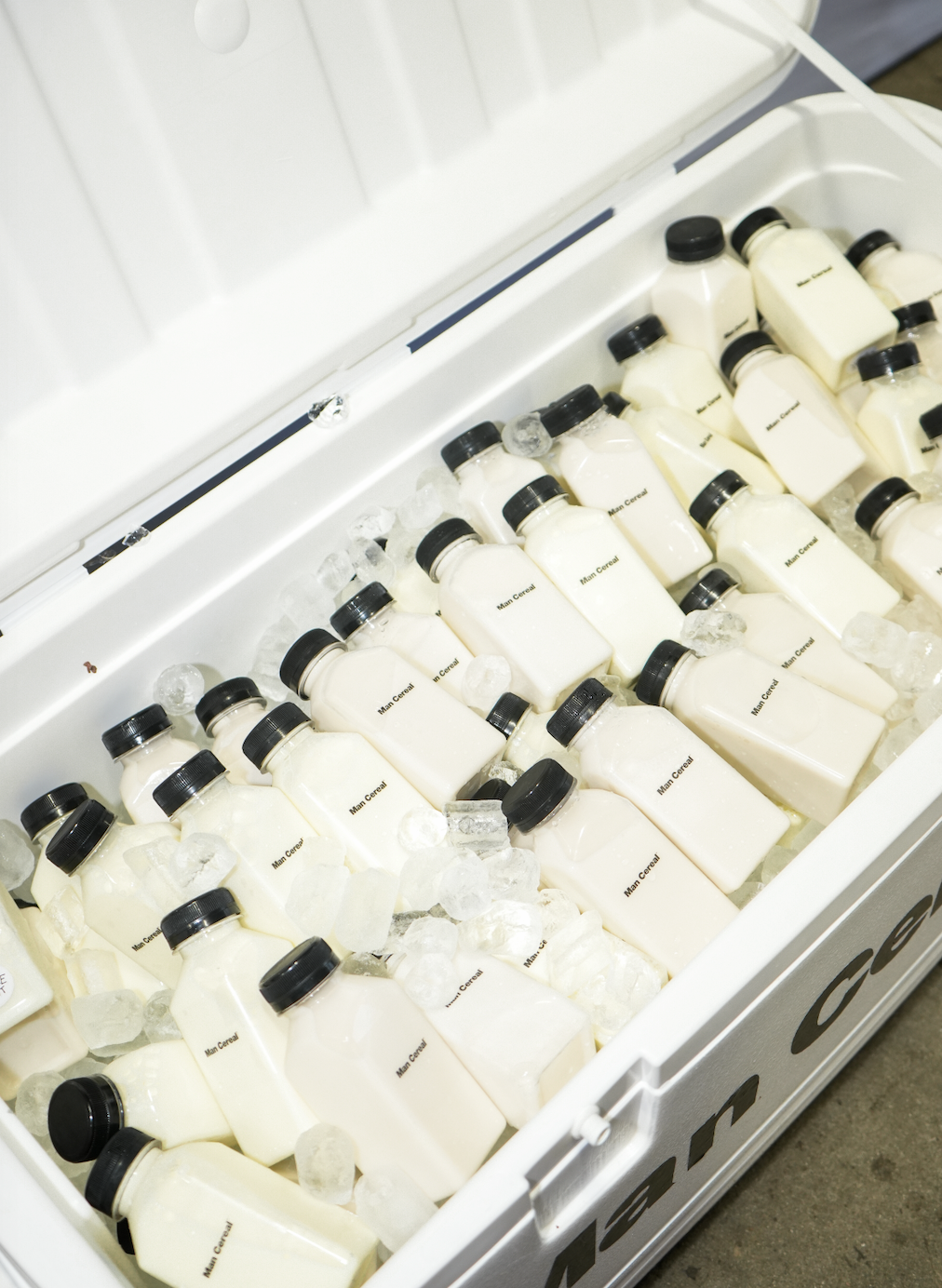 A cooler filled with bottles of milk surrounded by ice cubes.