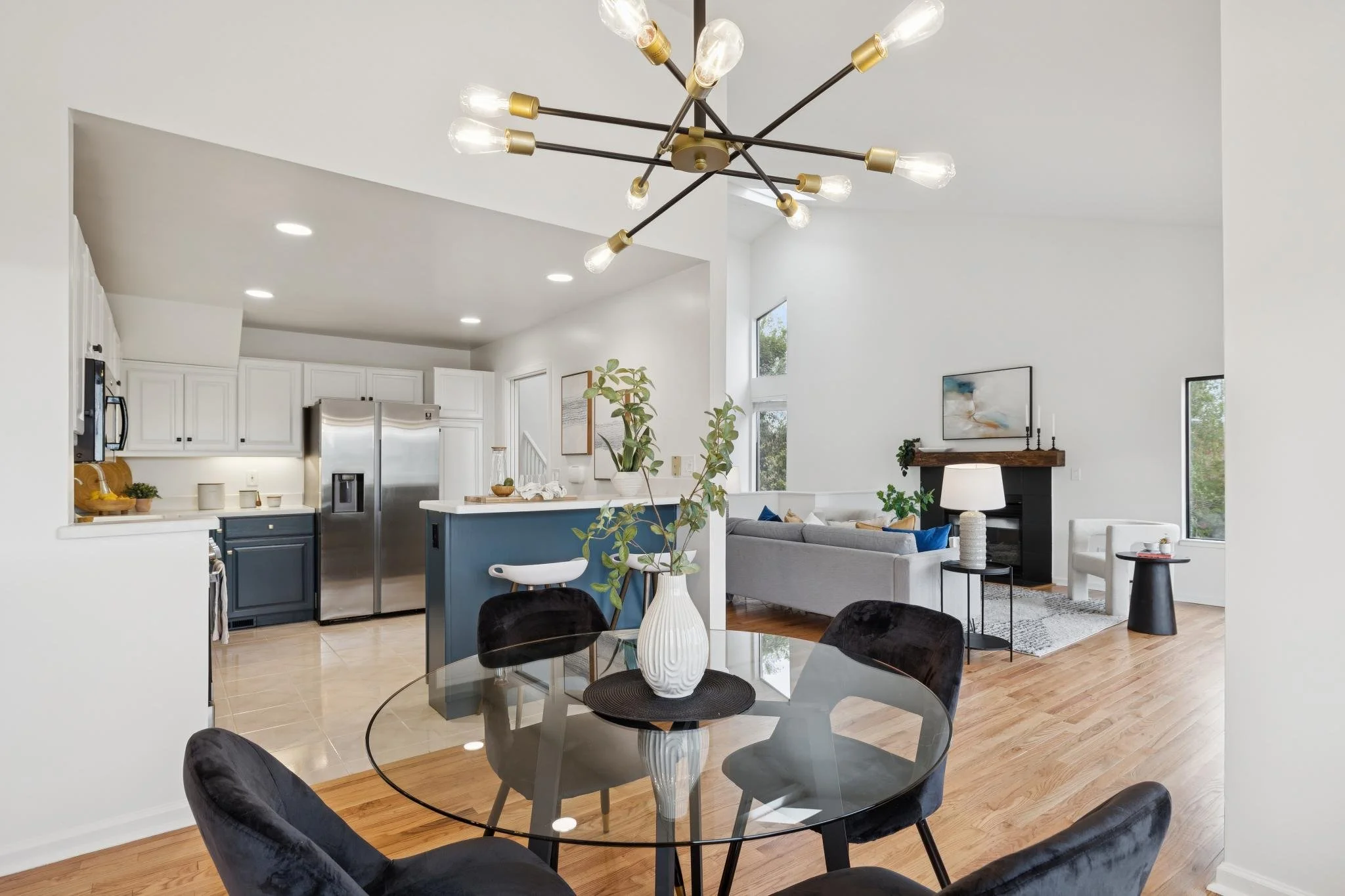Open-concept living space featuring a kitchen, dining area, and living room with large windows and modern decor.