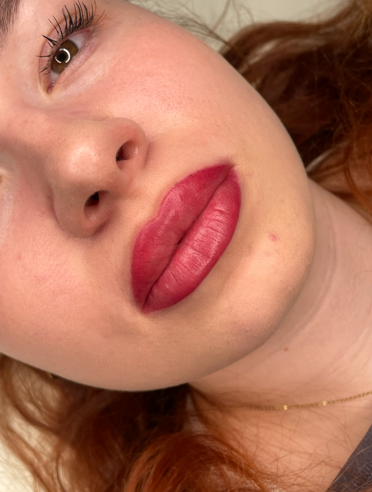 Nahaufnahme eines Gesichts mit roten, vollen Lippen und braunen Augen.