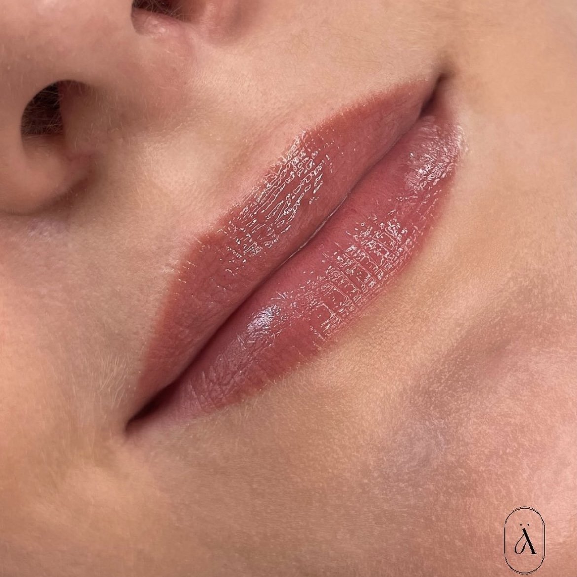 Nahaufnahme von glitzernden, gepflegten Lippen und einem Teil der Nasenspitze.