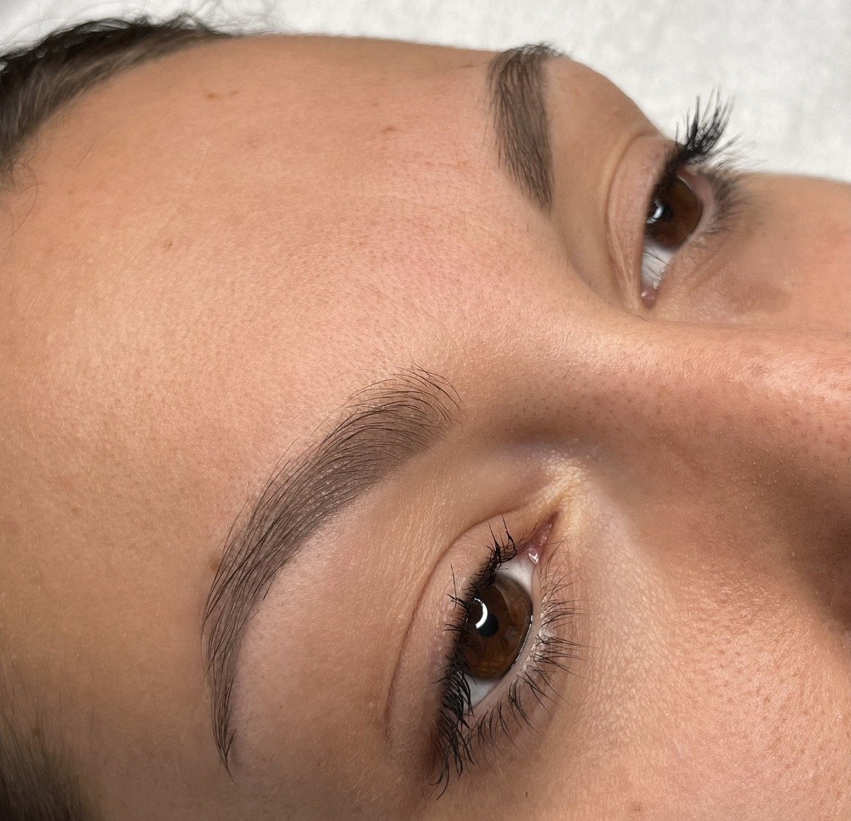 Nahaufnahme eines menschlichen Gesichts mit Fokus auf die Augen und die Augenbrauen, die Haut ist glatt und gepflegt.