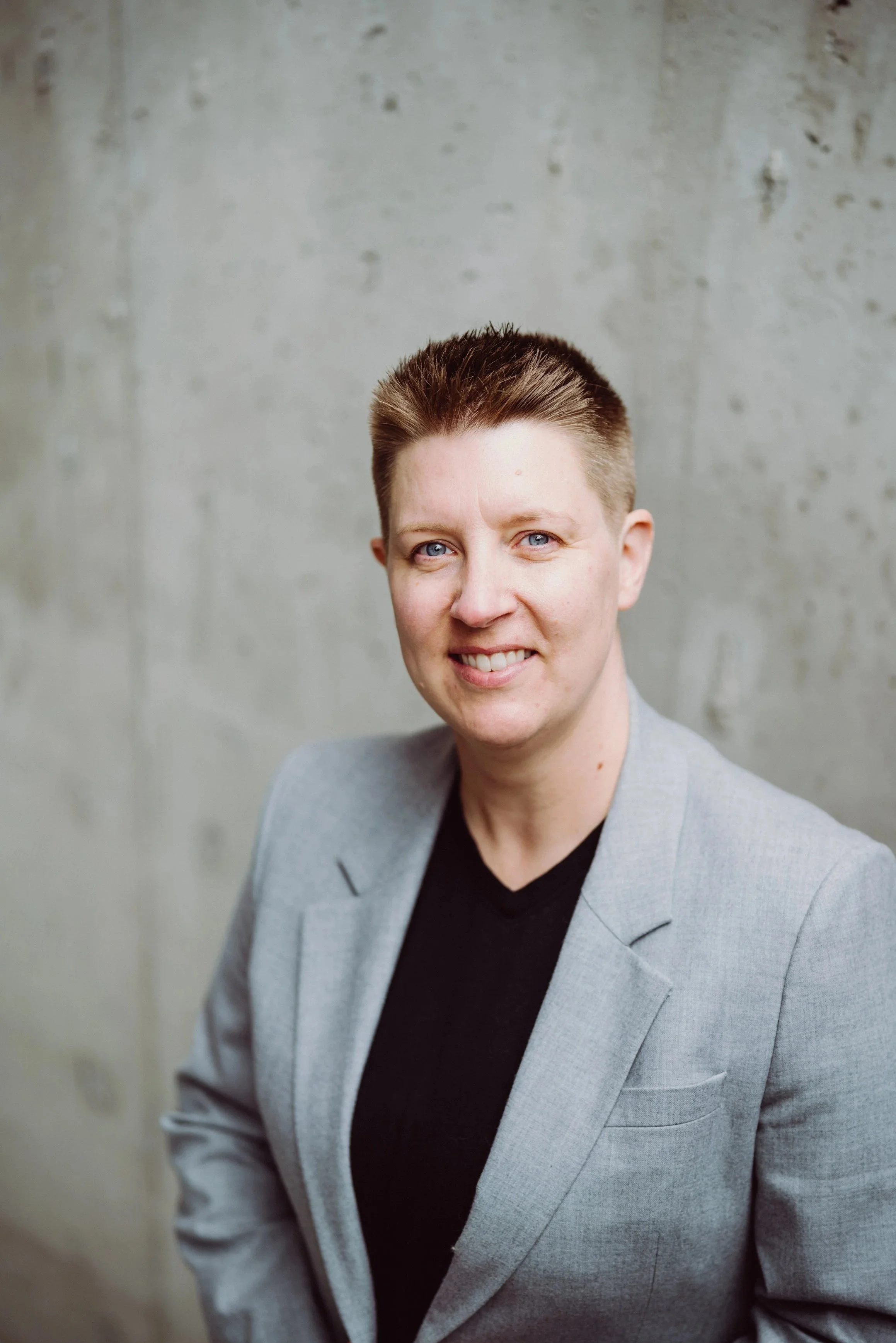Courtney Westwood, event strategy and operations consultant, smiling against a concrete wall.