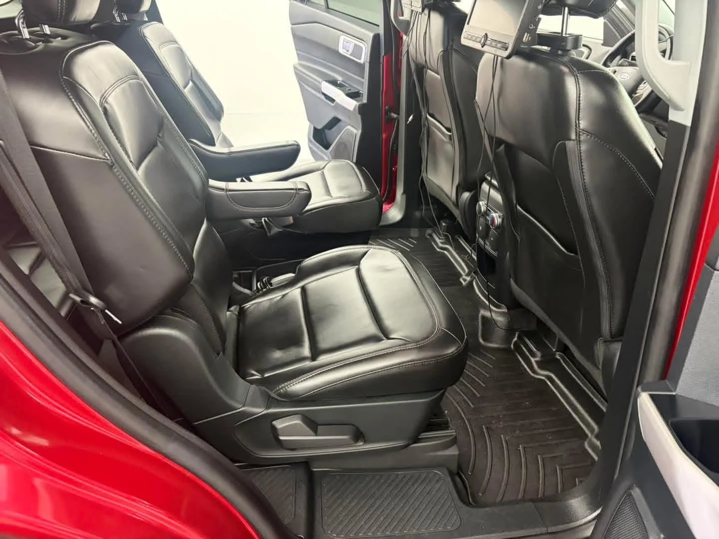 Interior of a vehicle showing black leather seats, with a focus on the rear seating area with three seats, and part of the front seats and dashboard in view.