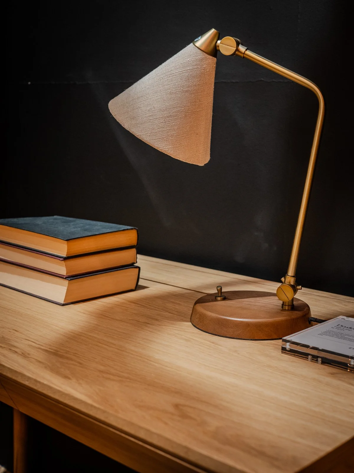 A wooden desk with a modern gold and wood desk lamp.