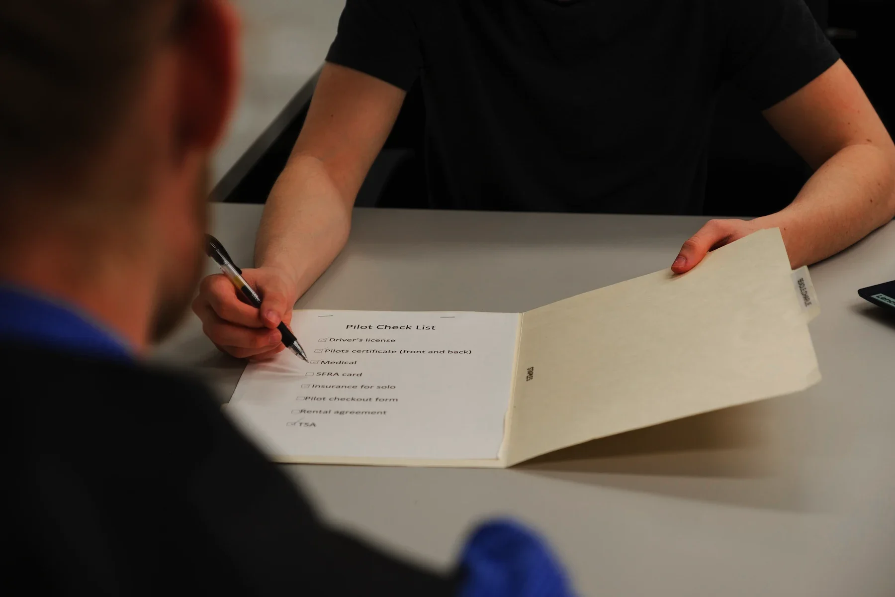 Person filling out a pilot check list with a pen, indicating a preparatory process for flying.