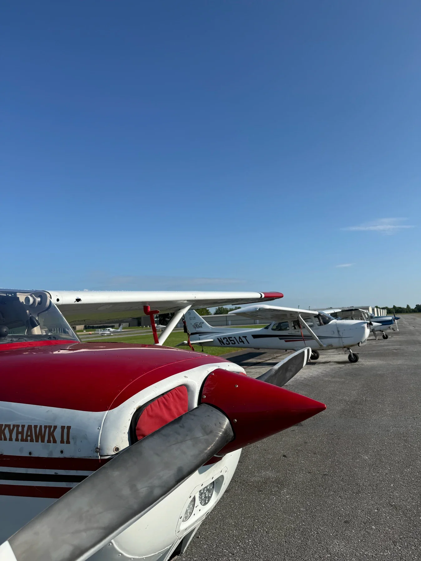 Multiple small aircraft parked on an airfield under a clear blue sky, with visible landing gear and propellers.