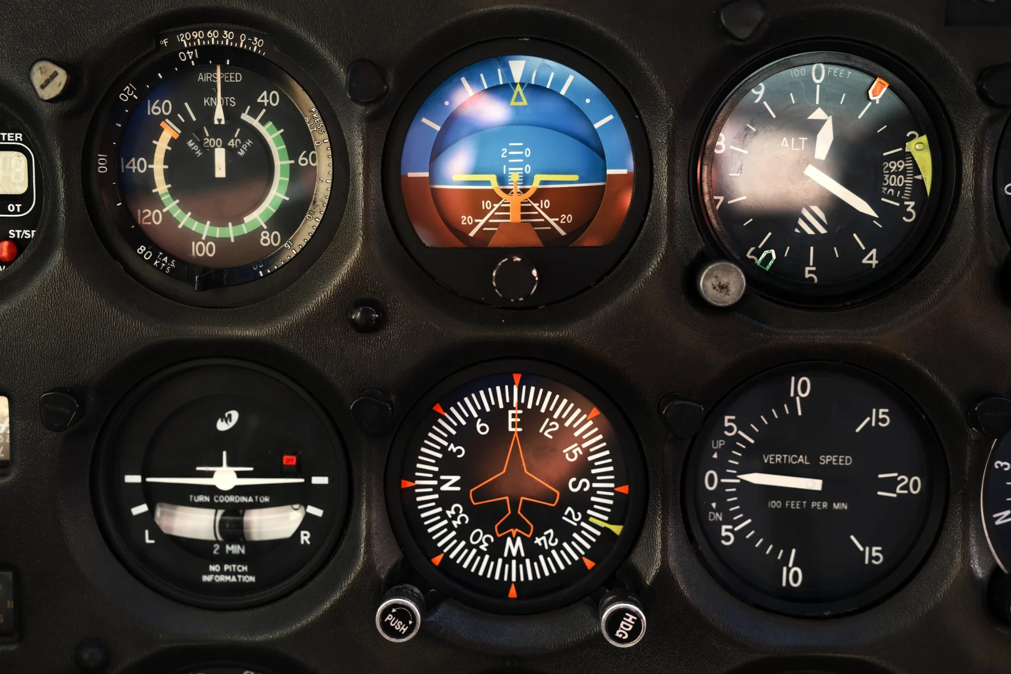 Dashboard of an aircraft cockpit with various gauges, including airspeed indicator, altimeter, vertical speed indicator, turn coordinator, and heading indicator.