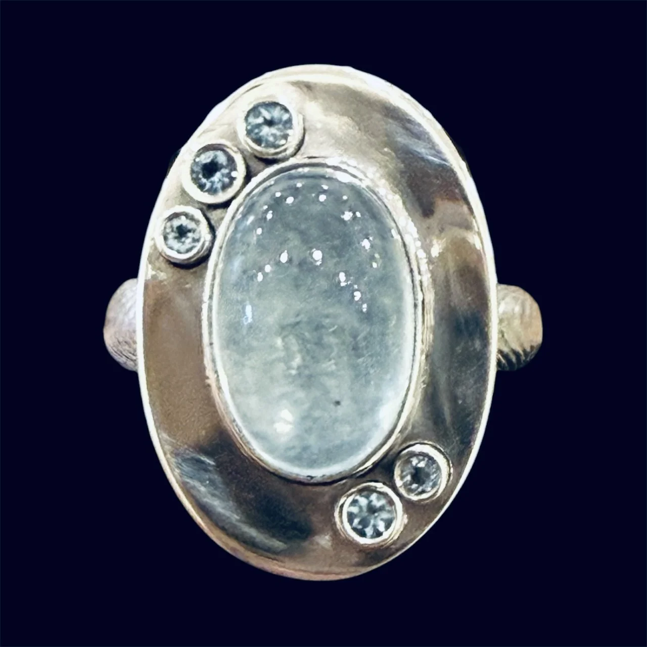 Sterling silver memorial ring with an aquamarine cabochon and five faceted aquamarine accents. Her son’s ashes are securely sealed in resin beneath the center stone.