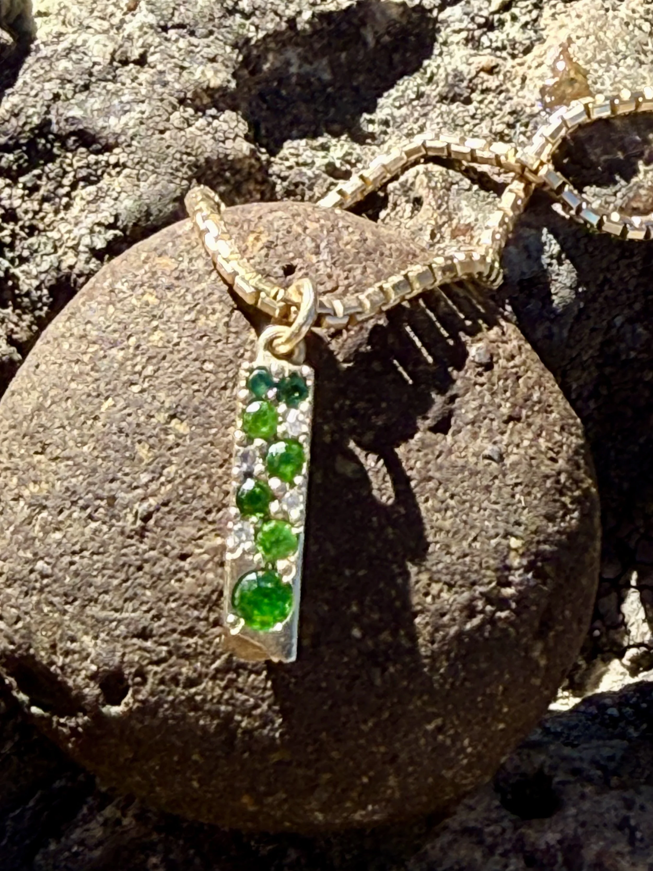 Organic bar necklace in recycled 14K gold, bead set with emeralds, green tourmaline, and diamonds.