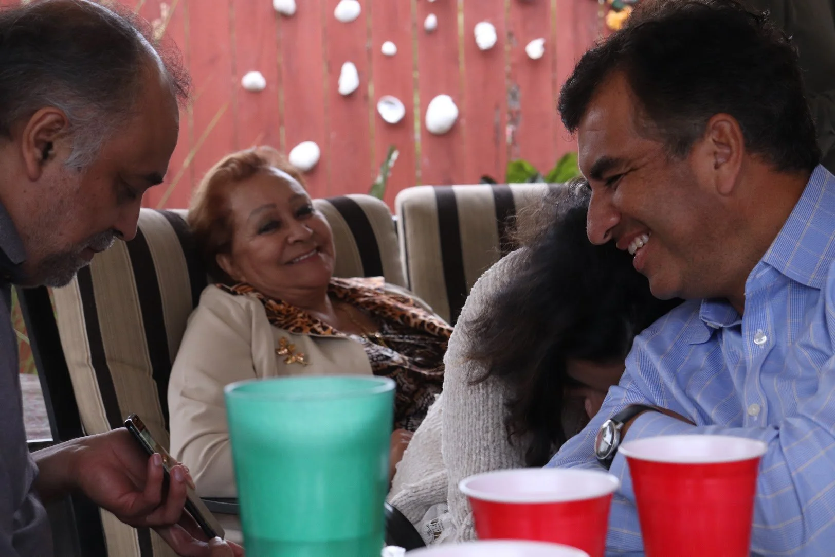 People sitting at a table, smiling and laughing, during a social gathering or celebration.
