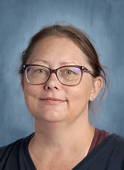 Portrait of a middle-aged woman wearing glasses against a blue background