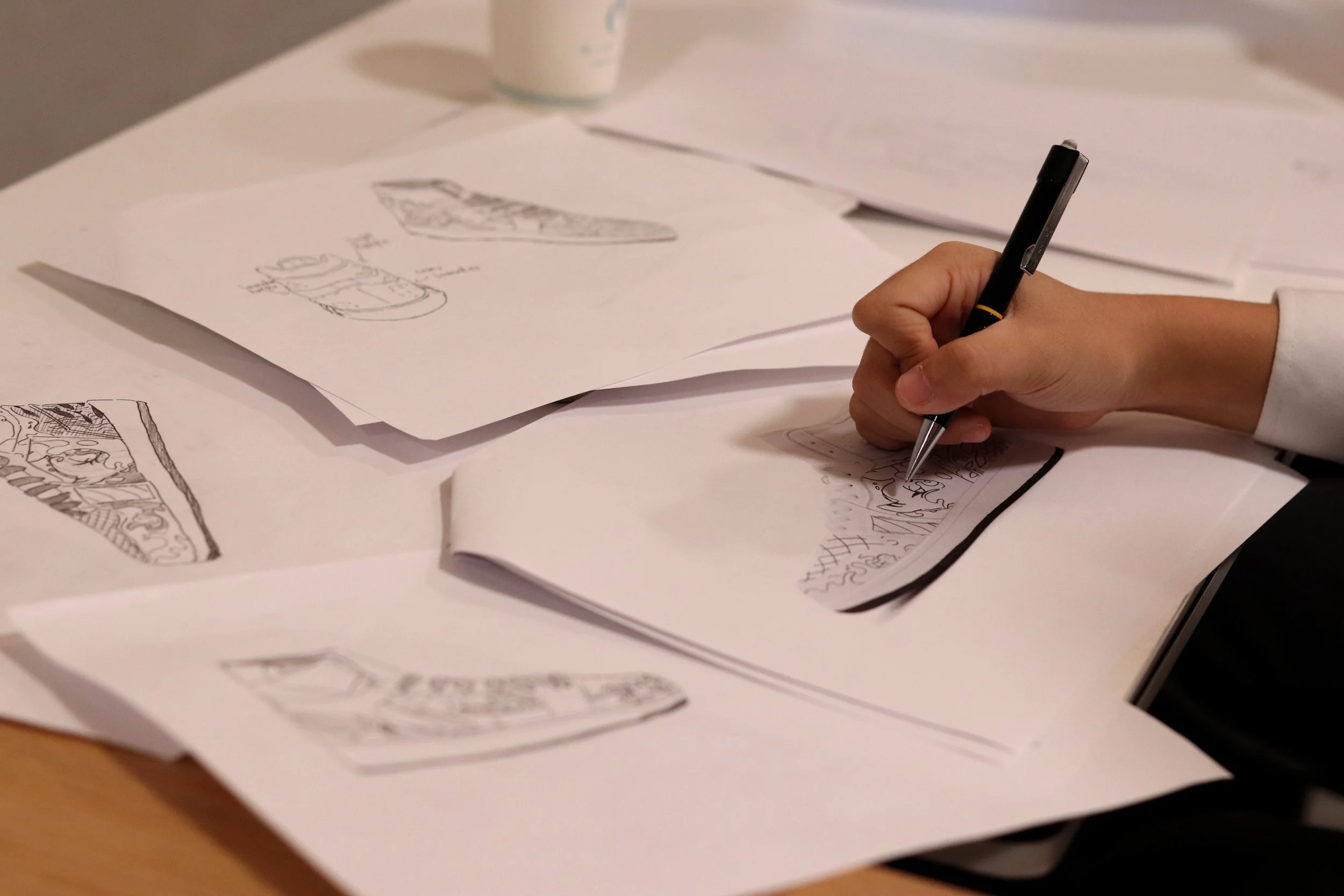 Person sketching with a black pen on sheets of paper