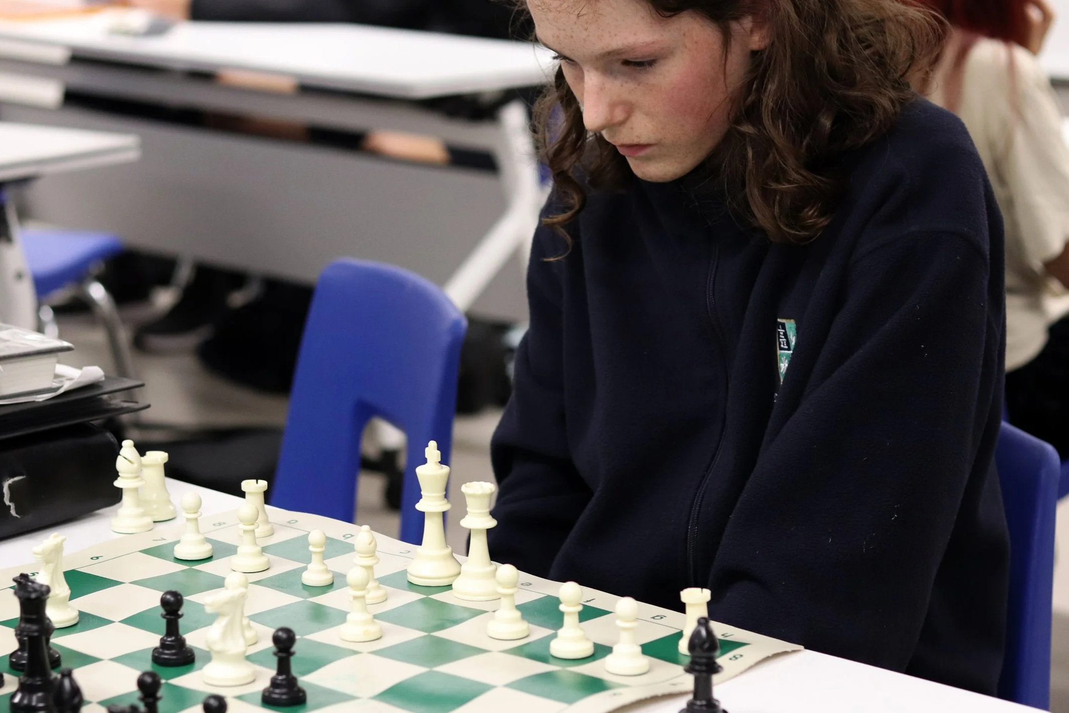 Young person concentrating over a chessboard during a game in a classroom